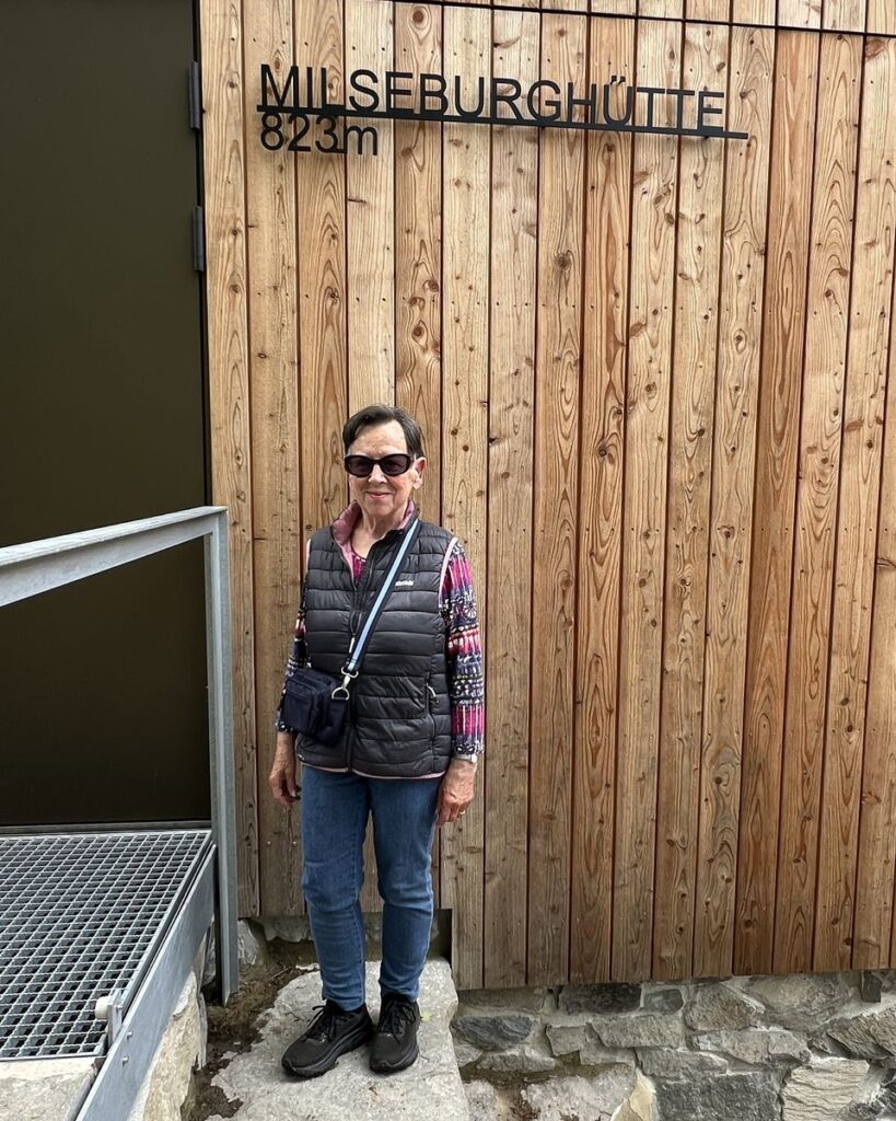 Wanderin steht vor der Milseburghütte unter dem Schriftzug Milseburghütte 823 m