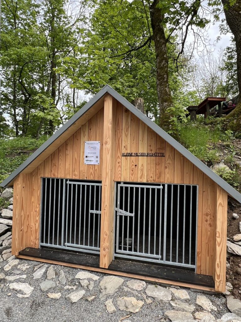 Kleines Holzhaus mit Gittertüren neben der Milseburghütte, beschriftet mit „Kleine Milseburghütte“