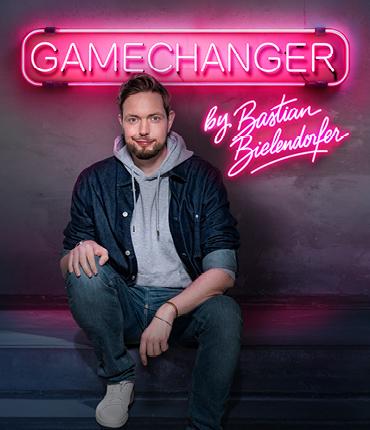 Comedian Bastian Bielendorfer sitzt vor dem Neon-Schriftzug GameChanger
