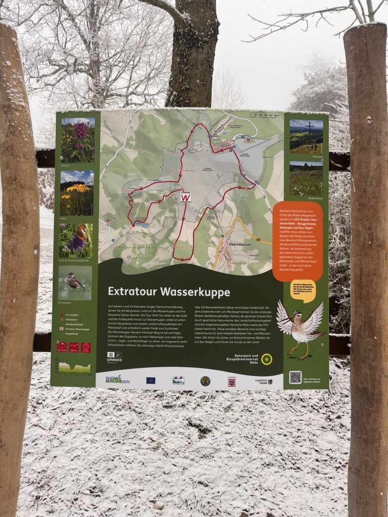 Verschneite Wandertafel der Extratour Wasserkuppe mit Karte und Wegzeichen W am Start am Guckaisee