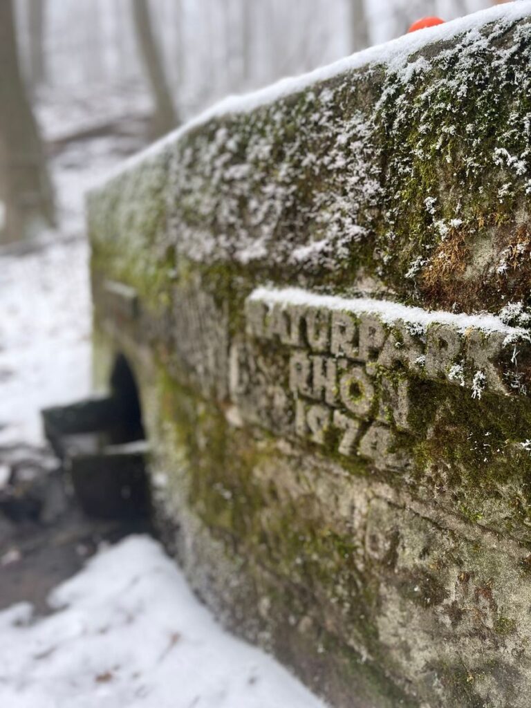 Verschneiter Steinblock mit Moos und der eingemeißelten Inschrift Naturpark Rhön 1974