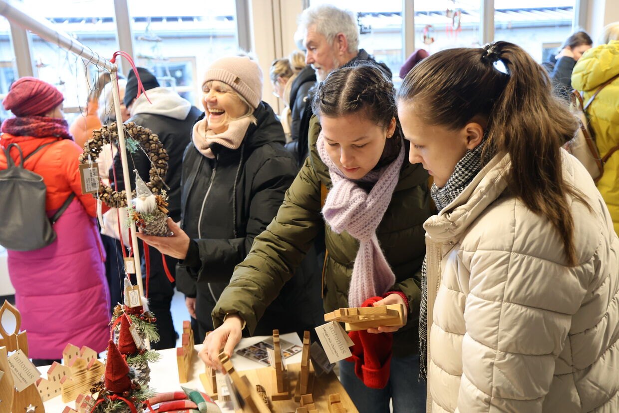Besucherinnen an einem Stand mit Holzdeko beim Adventsmarkt bei antonius