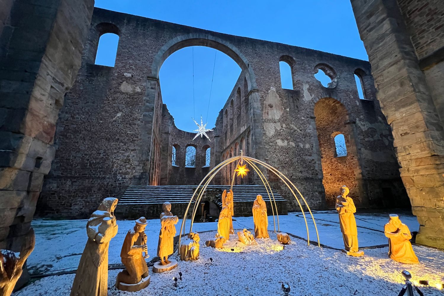 Beleuchtete Krippenfiguren aus Holz im Schnee in der Stiftsruine Bad Hersfeld zur blauen Stunde