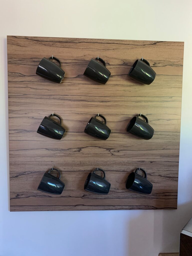Holzwand mit neun dunklen Tassen in der Küche der BUDE.29