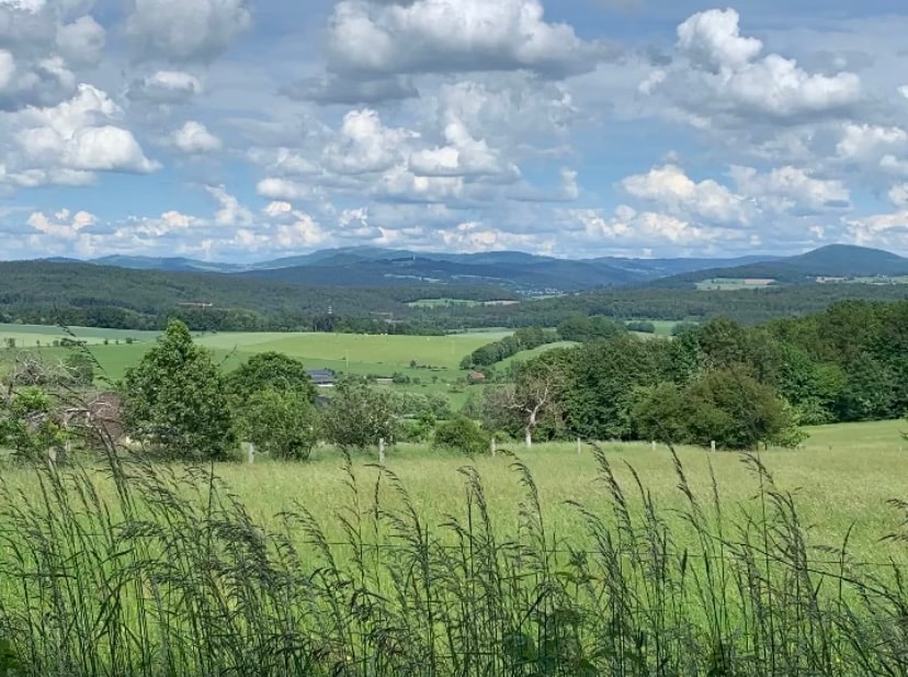 Blick über Wiesen und Wälder auf die Höhenzüge der Rhön