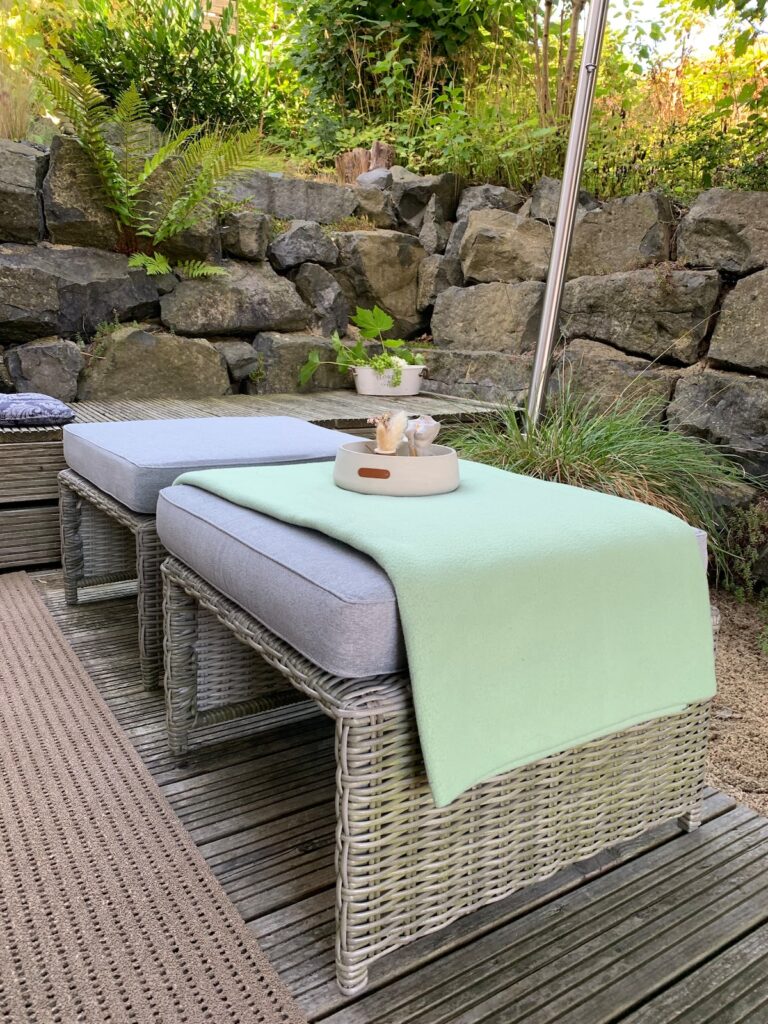 Loungemöbel auf der Terrasse der BUDE.29 vor einer Natursteinmauer