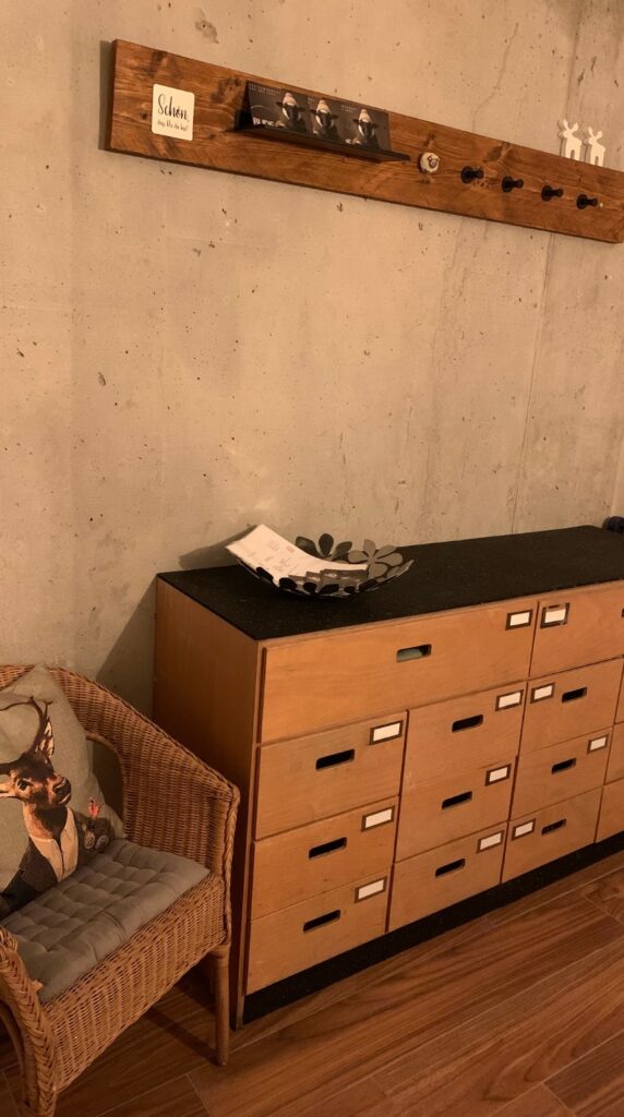 Windfang der BUDE.29 mit Garderobe, Kommode und Korbsessel