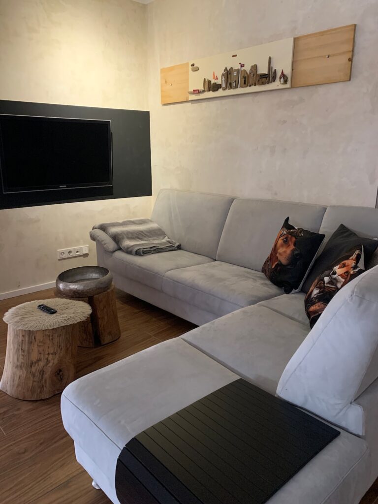 Wohnzimmer der BUDE.29 mit Ecksofa und Fernseher an der Wand