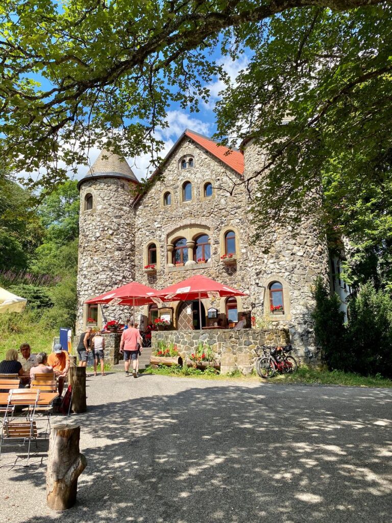 Biergarten mit roten Sonnenschirmen vor dem Jagdschloss Holzberghof
