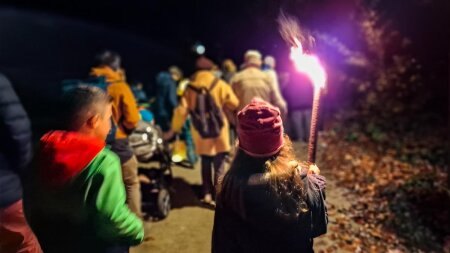 Teilnehmer eines abendlichen Laternen- und Fackelumzugs von hinten
