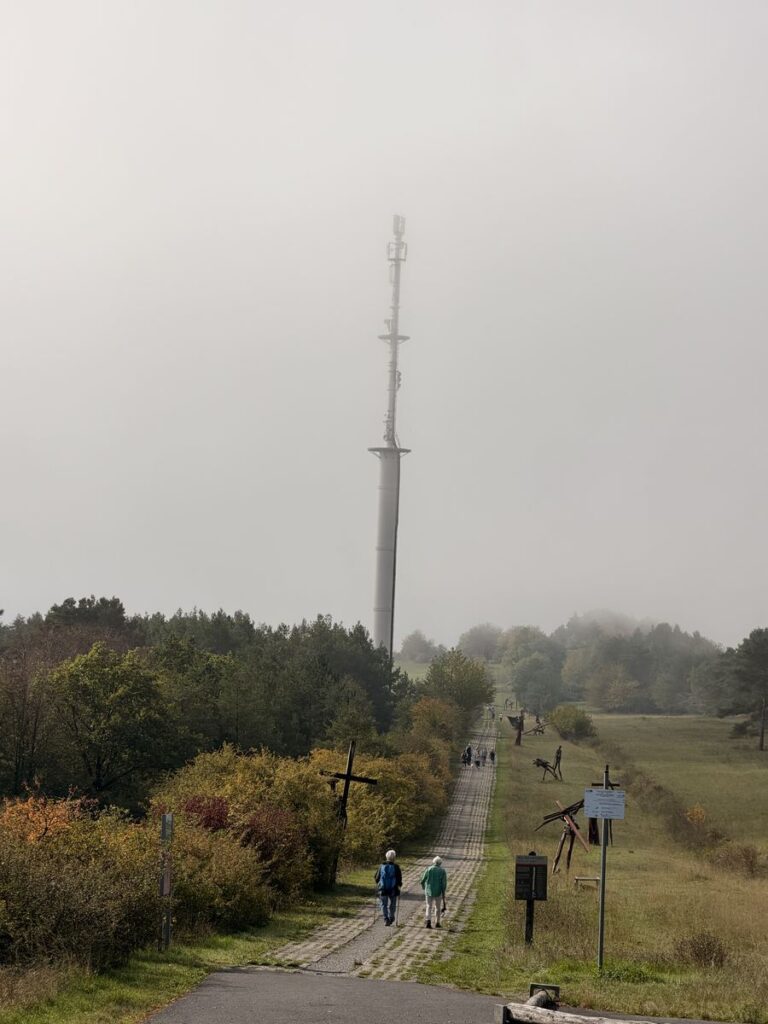 Weg der Hoffnung am Point Alpha: Kolonnenweg mit Eisenskulpturen, im Nebel ein Sendemast