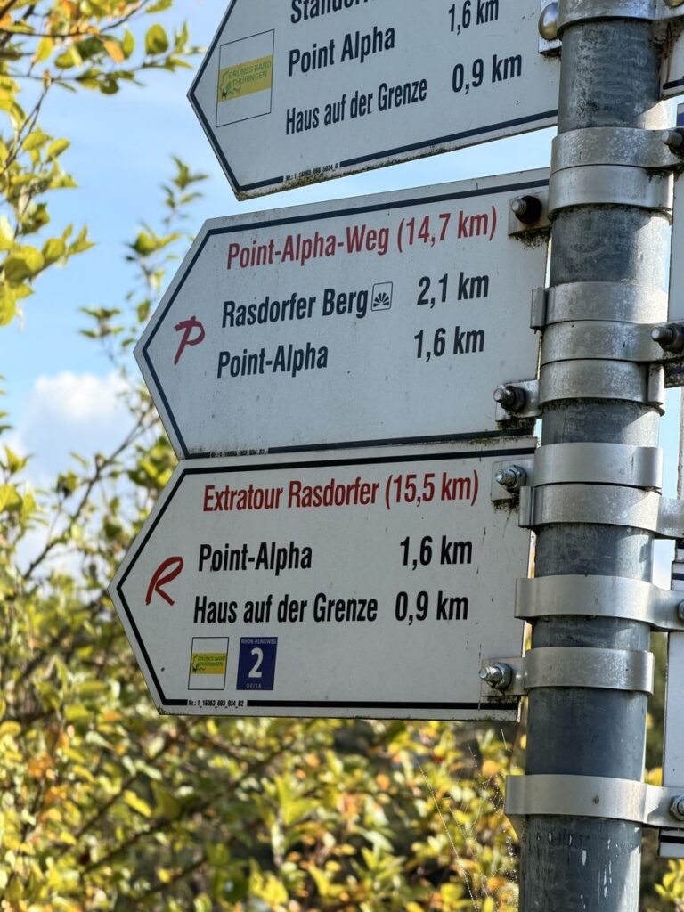 Wegweiser mit den Extratouren Point-Alpha-Weg und Der Rasdorfer sowie Haus auf der Grenze