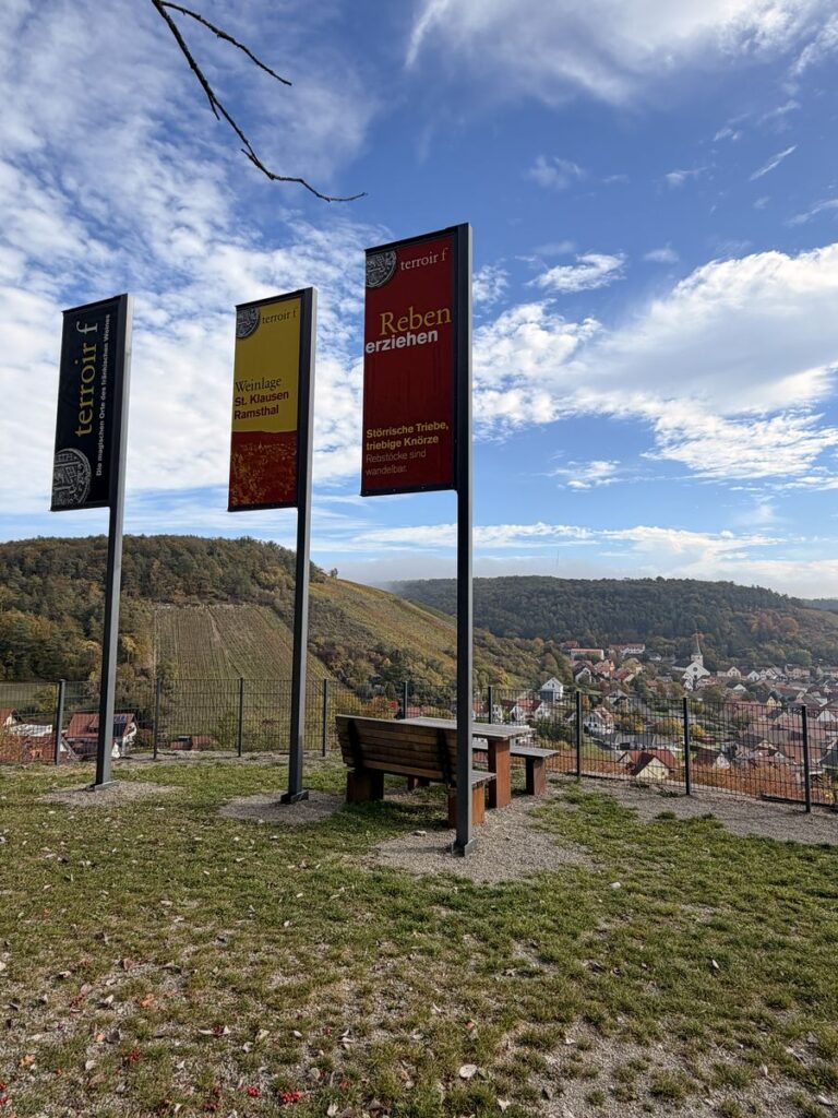 Aussichtspunkt terroir f mit drei Fahnen und Bank über den Weinbergen von Ramsthal