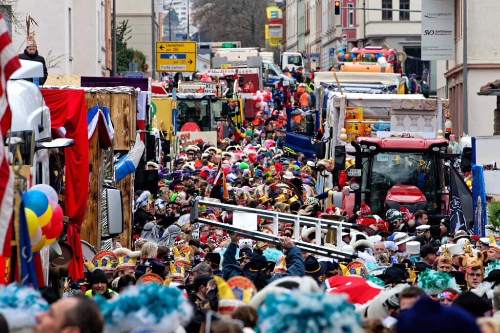 Blick von oben auf die Zugaufstellung des Fuldaer Rosenmontagszugs: Wagen, Traktoren und dicht gedrängte Fußgruppen in bunten Kostümen
