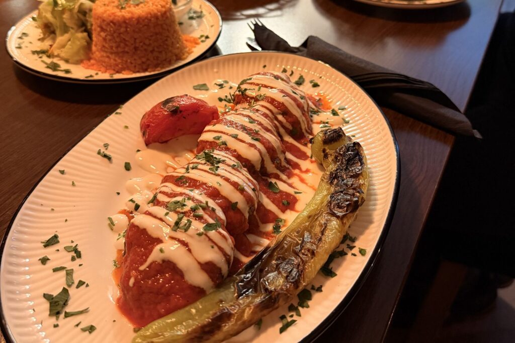 Beyti Soslu Köfte mit Tomatensauce und Knoblauchjoghurt im Tandurem in Fulda, dahinter Bulgur