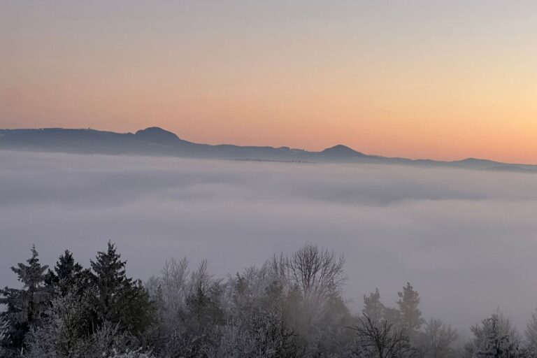 Kuppen der Rhön ragen bei Abendrot aus einem Nebelmeer