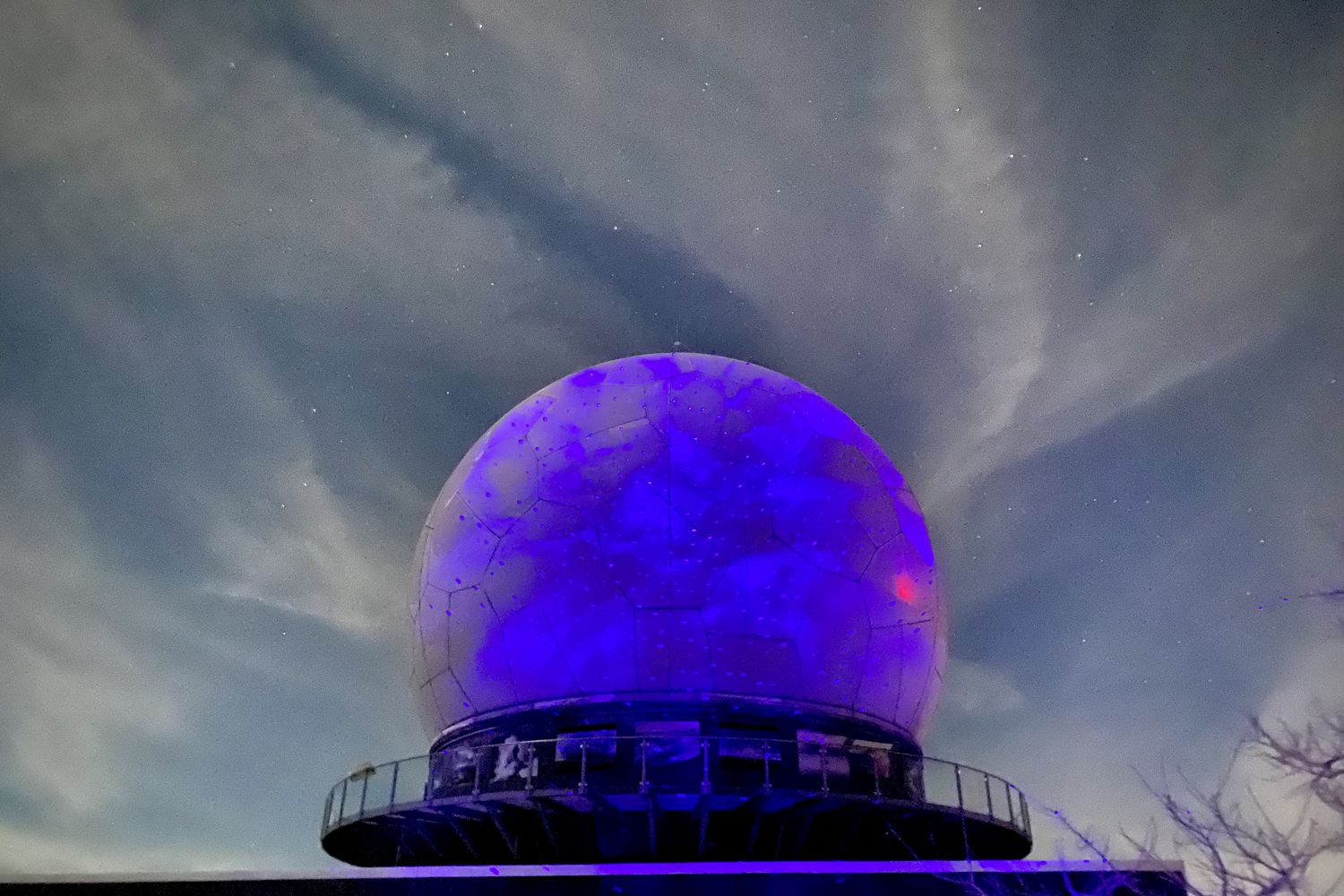 Das Radom auf der Wasserkuppe in einer Winternacht, mit einem Sternenhimmel-Projektor in Blau und Violett angestrahlt.