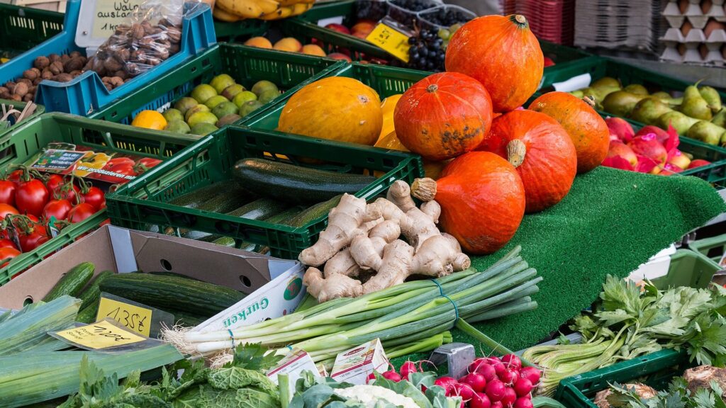 Marktstand mit Kürbissen, Gemüse und Obst in Kisten
